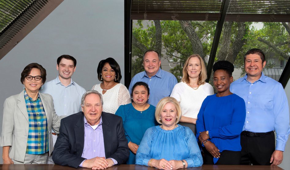 A group of eight diverse professionals gathered for a team photo in an office setting.