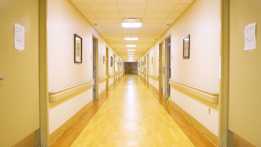 A serene hospital hallway with well-lit surroundings and framed artwork on the walls.