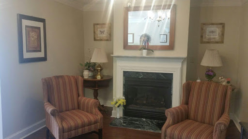 A cozy living room featuring striped chairs and a decorative fireplace.