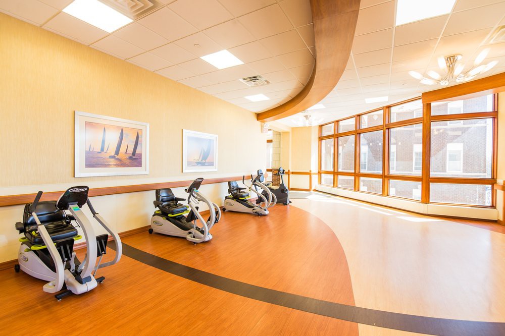 A well-lit rehabilitation center with modern exercise equipment and a curved pathway.