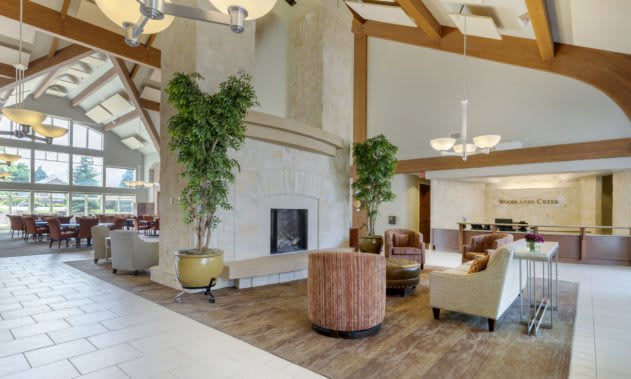 A spacious lobby featuring a fireplace, comfortable seating, and elegant chandeliers.