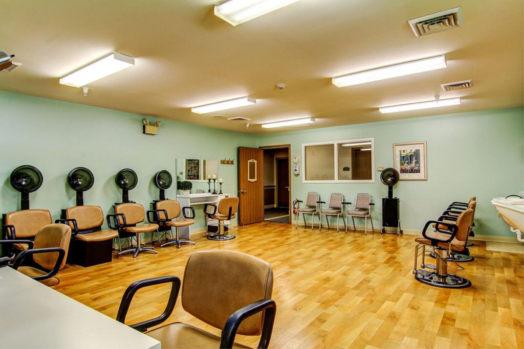 An interior view of a salon with multiple chairs and hair dryers lined against the wall.