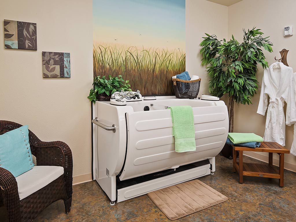 A wellness spa room featuring a hydrotherapy tub, surrounded by calming decor and relaxing elements.