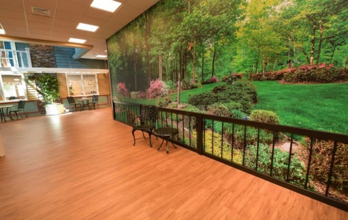 A hallway with a nature-themed mural on the wall, wooden flooring, and a bench.