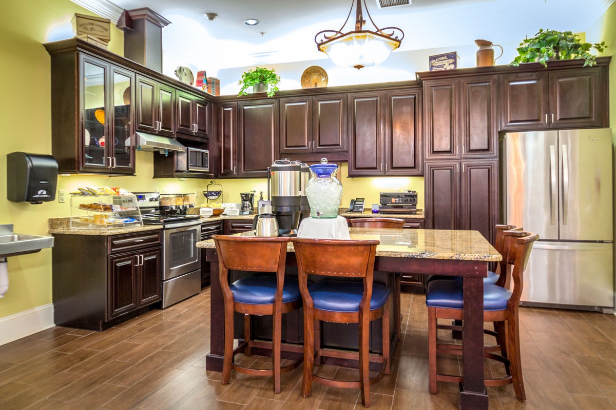 A modern kitchen with wooden cabinets, a central island, and bar stools.