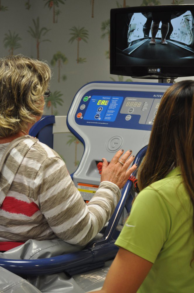Two individuals are using exercise equipment for rehabilitation purposes indoors.