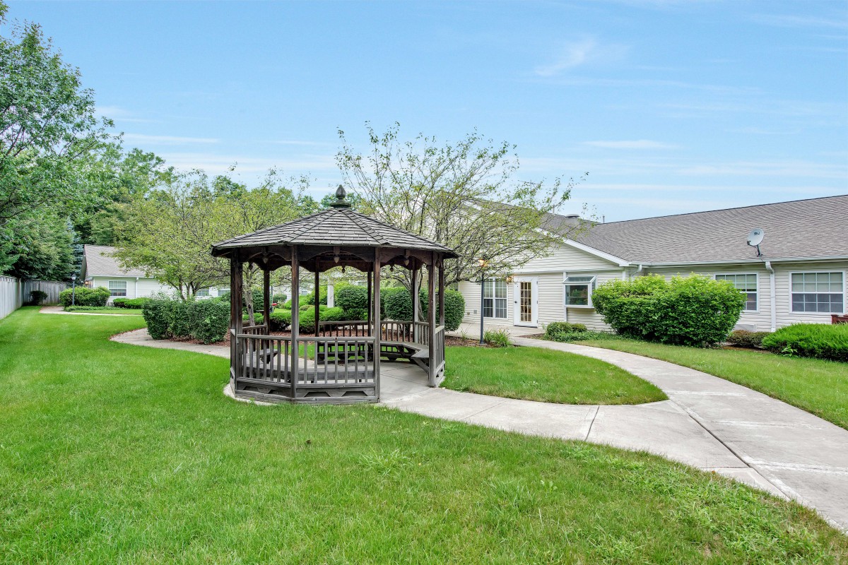 A scenic garden with a gazebo and winding pathway leading to a building.
