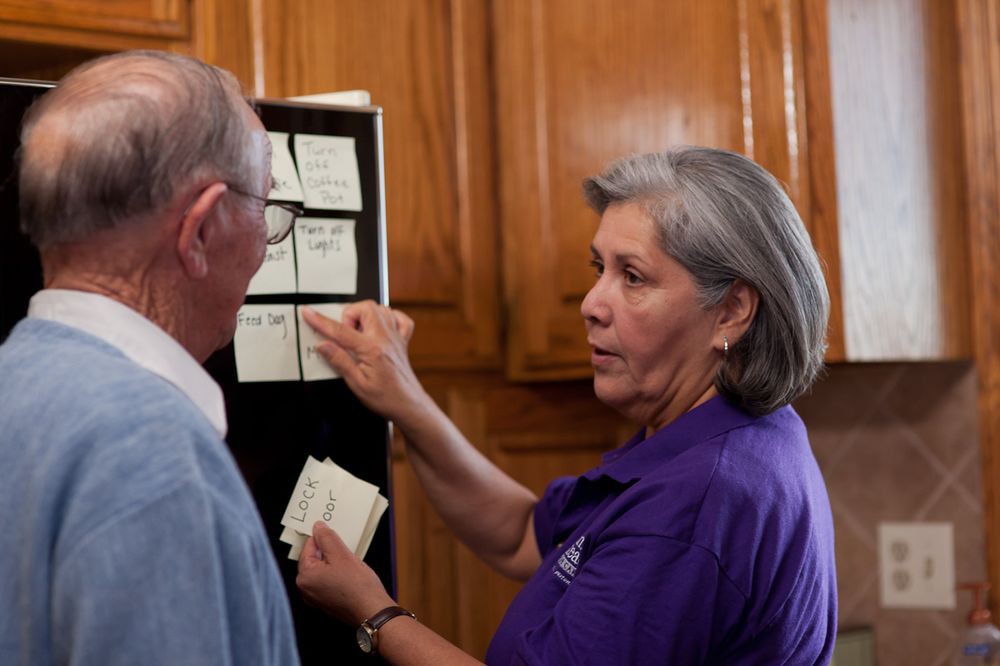 An elderly woman explaining a concept using post-it notes to an older man.