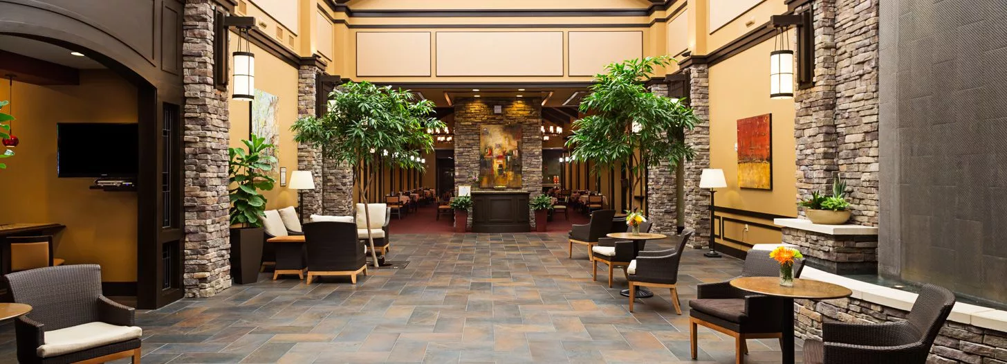 A spacious lobby with comfortable seating, greenery, and elegant decor.