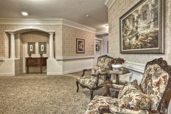 A traditional-style interior hallway with ornate chairs and artwork on the walls.