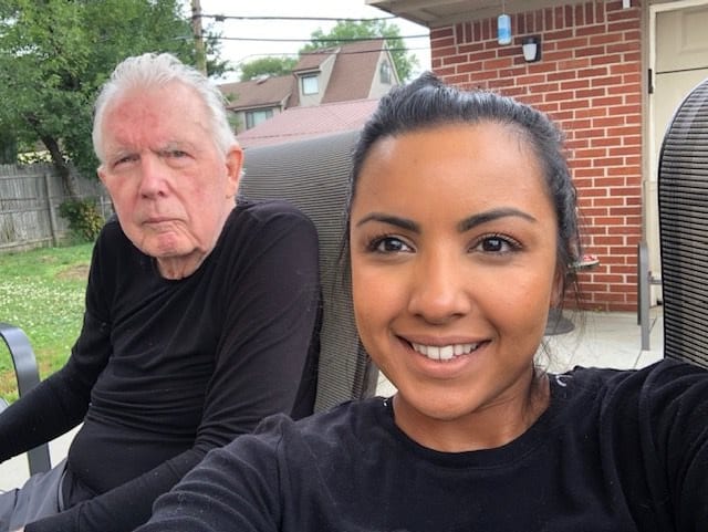 Two people taking a selfie outdoors, one smiling at the camera.