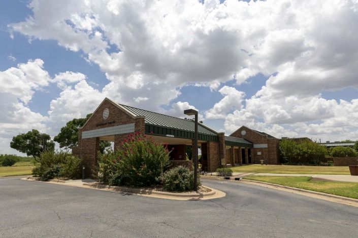 A brick building with a drive-through area under a partly cloudy sky.