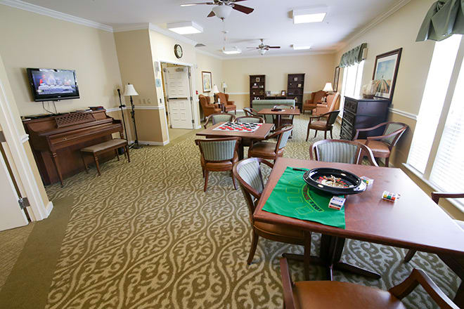 A cozy living room with multiple tables and chairs, a piano, and decorative carpet.