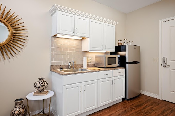 A compact kitchen area with white cabinets, a microwave, and a mini fridge.