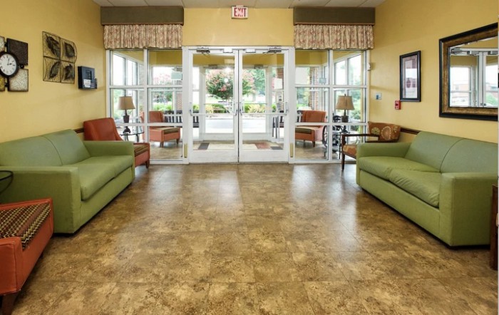 A spacious lobby with green sofas, large windows, and glass doors leading outside.