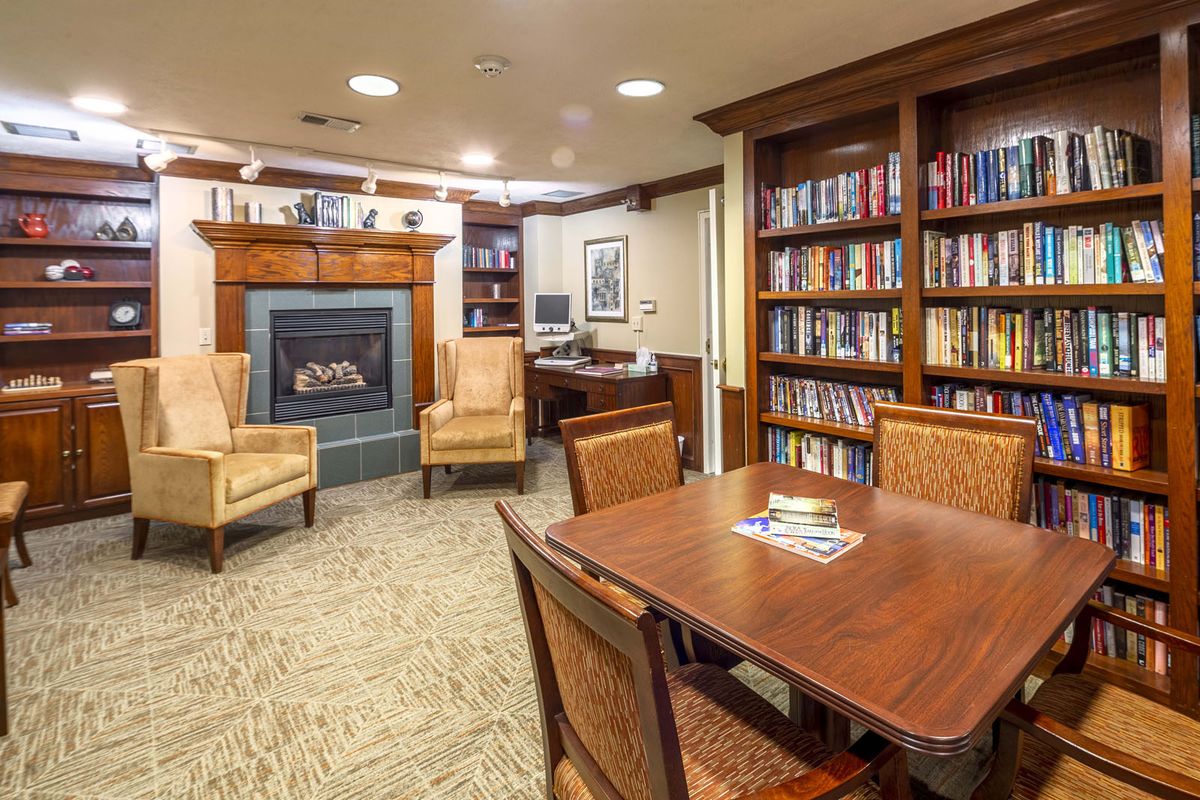 Cozy library with a fireplace, surrounded by bookshelves and seating.