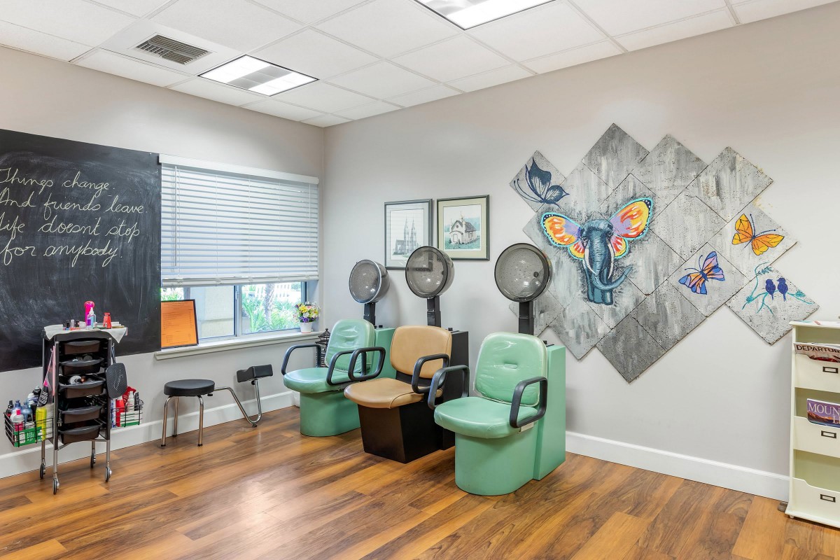 A modern salon interior with multiple hair drying stations and colorful wall art.