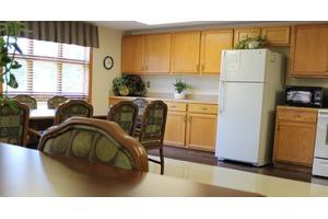 A cozy kitchen and dining area with wooden cabinets, a refrigerator, and a dining table with chairs.