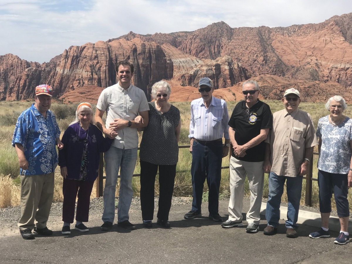 A group of people standing together in front of a scenic mountainous landscape.
