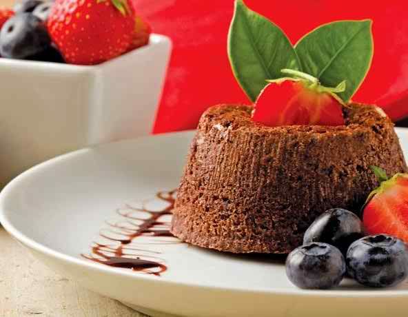 A beautifully plated chocolate dessert with fresh strawberries, blueberries, and mint leaves.