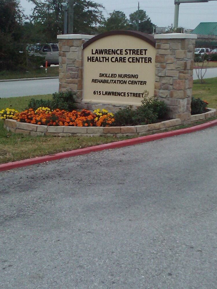 Entrance sign for Lawrence Street Health Care Center with a flowerbed.