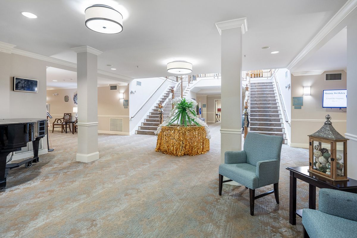 A spacious lobby with a central staircase, elegant decor, and comfortable seating.