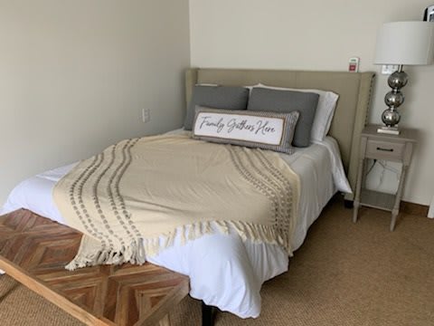 A cozy bedroom with a neatly made bed featuring neutral-colored bedding and decorative pillows.
