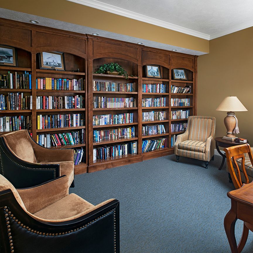 A cozy library room with bookshelves and comfortable seating.