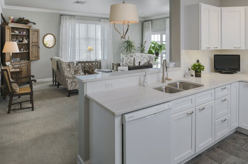 A modern kitchen with white cabinetry opens up to a spacious living area.