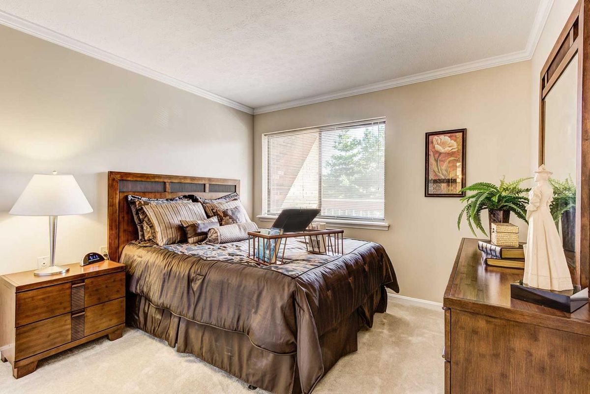 A cozy bedroom with a wooden bedframe and large window.