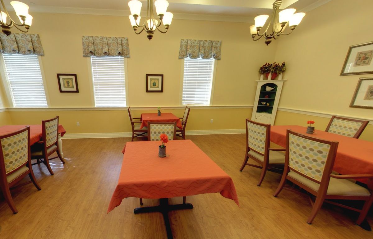A cozy dining room with tables and chairs, decorated with chandeliers and curtains.