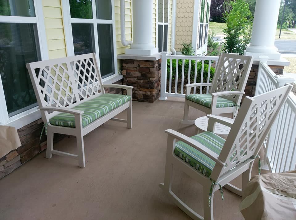 Outdoor porch area with white lattice furniture and green cushions.