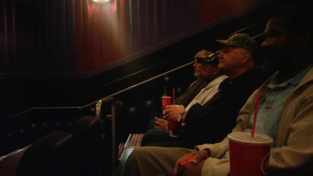 Audience members seated in a movie theater, enjoying snacks and watching the screen.
