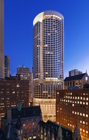 A tall skyscraper illuminated at night in a bustling cityscape.