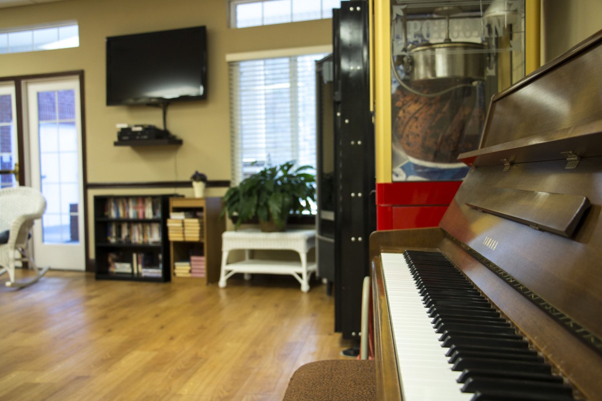 A cozy living room with a piano, television, and bookshelf.
