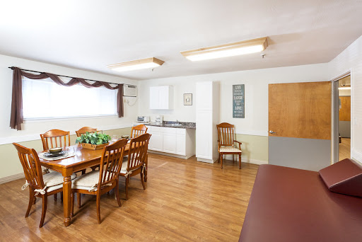 A cozy dining area featuring wooden furniture and a kitchen space, designed for casual gatherings.