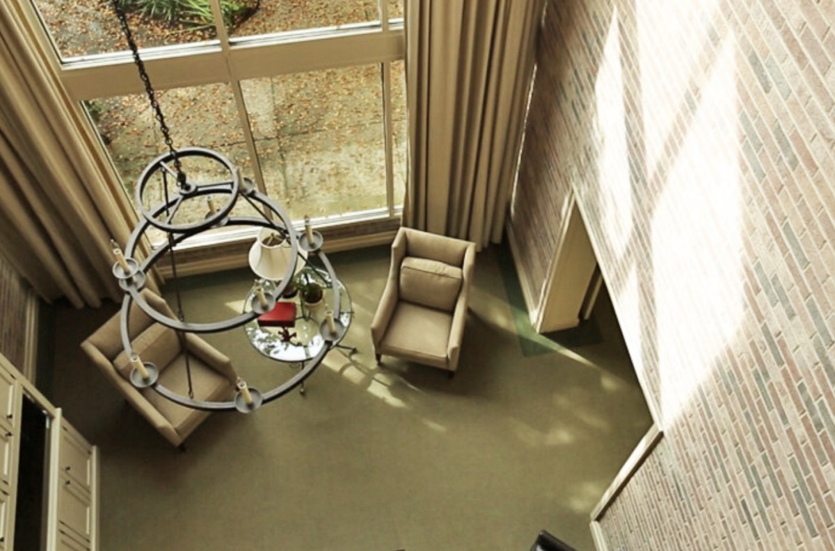 A cozy living room featuring two armchairs and a coffee table, bathed in natural light from large windows.