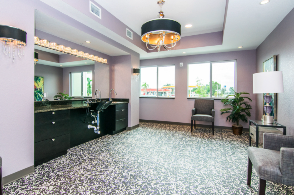 A modern interior room with a chandelier, large mirrors, and ample natural light from the windows.