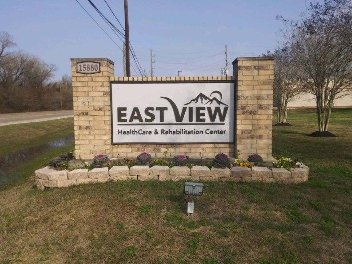 Sign for East View Healthcare & Rehabilitation Center displayed outdoors with brick pillars.
