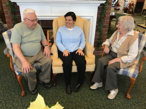 A friendly gathering of three seniors enjoying a moment together in a cozy indoor setting.