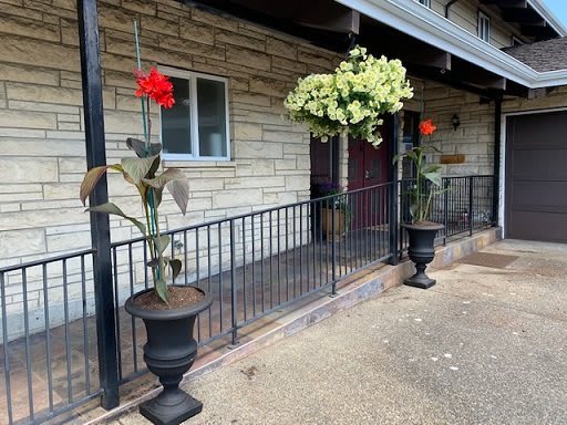 Two large planters with red flowers and hanging greenery stand outside a building with a stone wall facade.