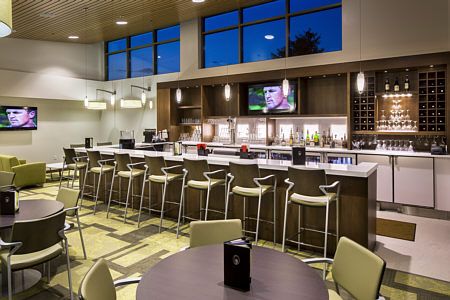 A modern bar and dining area with high chairs and a television, set in an elegant interior.