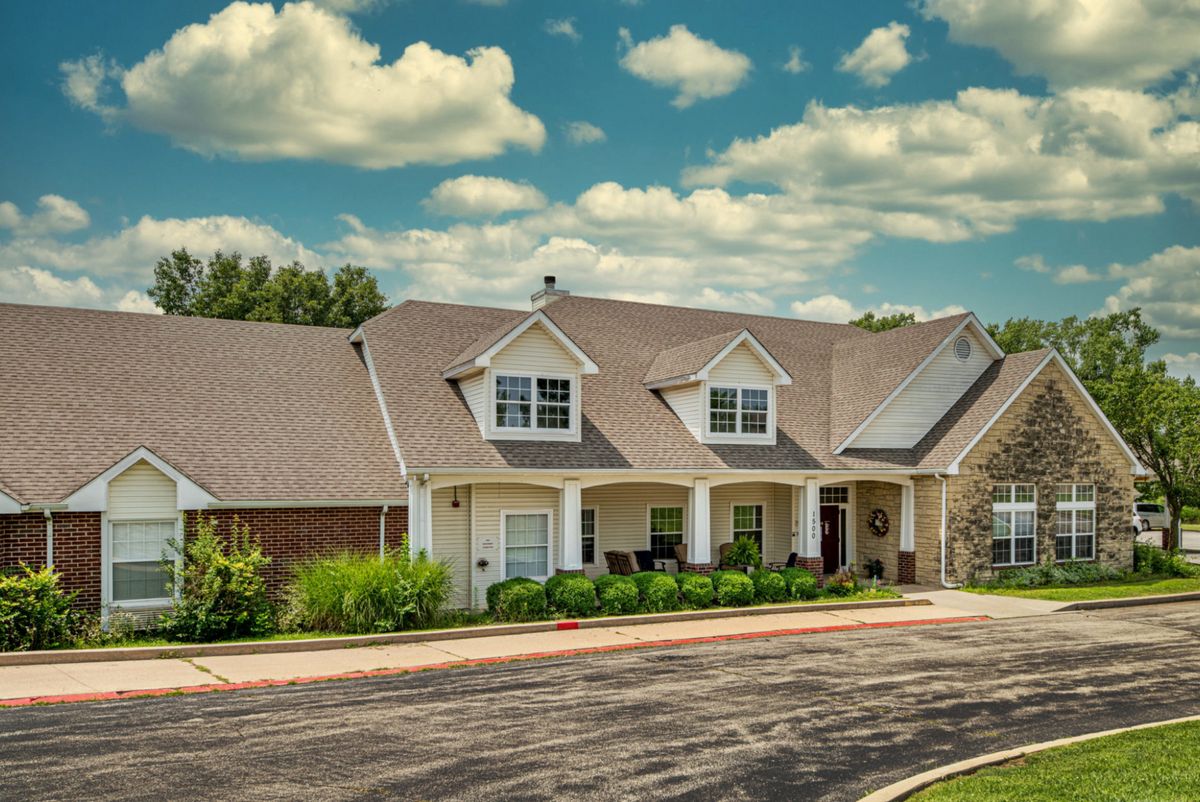 A suburban house with a spacious driveway under a partly cloudy sky.