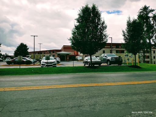 A view of a building with several cars parked in front, set against a cloudy sky.