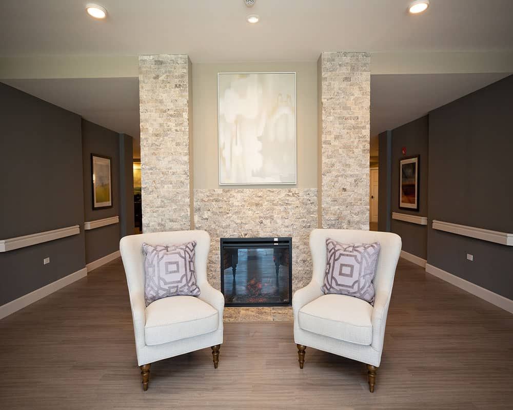 A modern living room with a fireplace and two elegant armchairs.