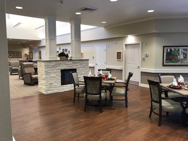 A cozy dining area with a central fireplace and elegant seating arrangements on hardwood flooring.