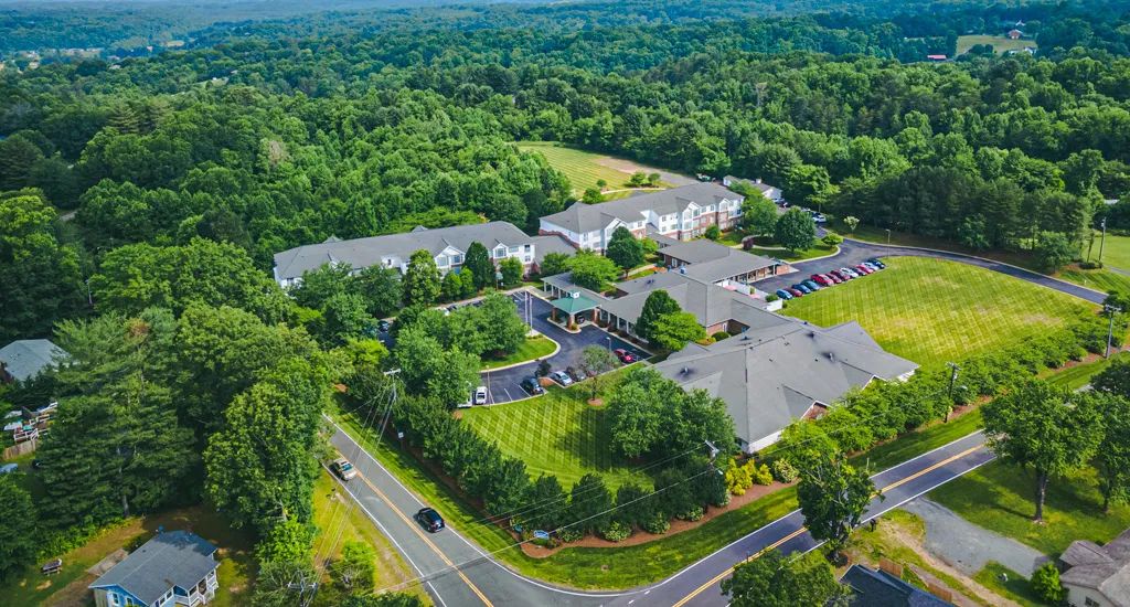 Aerial view of a large building complex surrounded by trees and greenery.