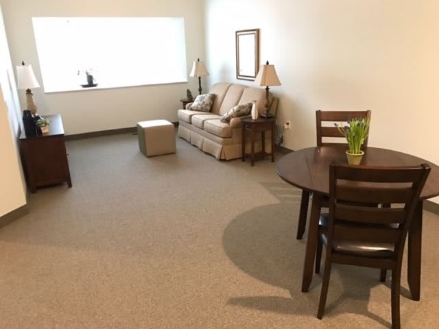 A cozy living room with a sofa, table, and chairs.