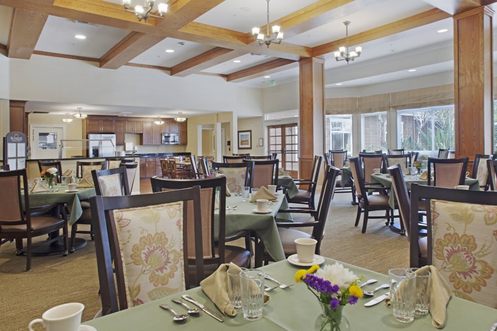 Elegant dining area with neatly arranged tables and chairs under ornate chandeliers.