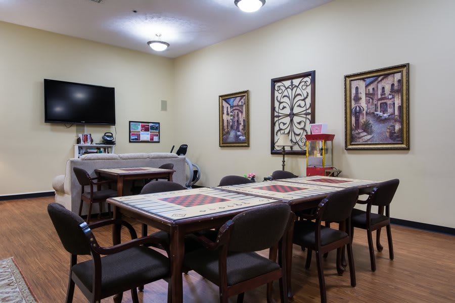 A cozy dining area with tables and chairs, decorated with artwork and a television.